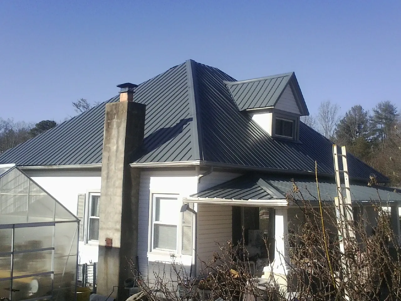 Dark blue standing seam metal roof on a white farmhouse with dormer — Slate & Tile Roof Repair by Roofing Brothers in Ukiah