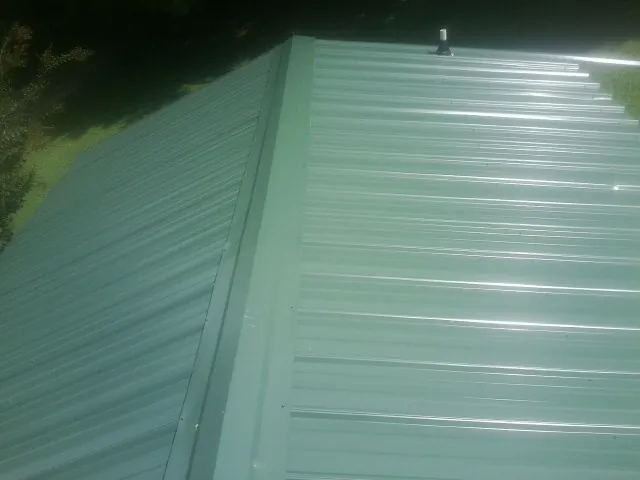 New green metal panels meeting at the ridge of a roof — Flat Roof Repair work by our crew in Ukiah