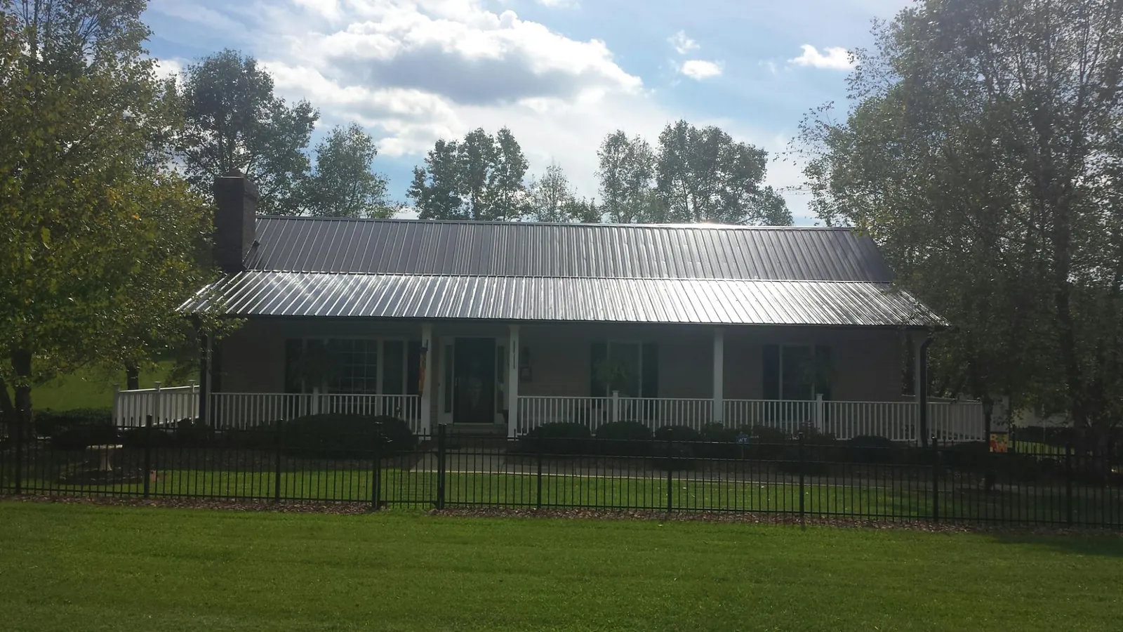Gray metal roof on a brick ranch with a full width front porch — Gutter Guard Installation work by our crew in Ukiah