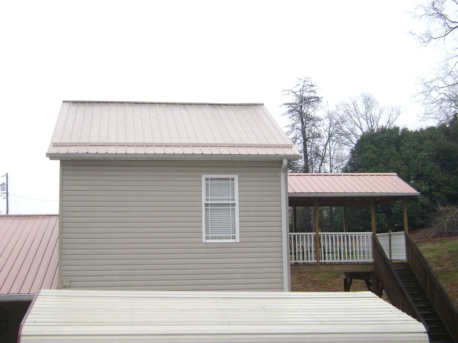 Tan metal roofs on a two story addition and attached porch, from a Roof Replacement job in Ukiah
