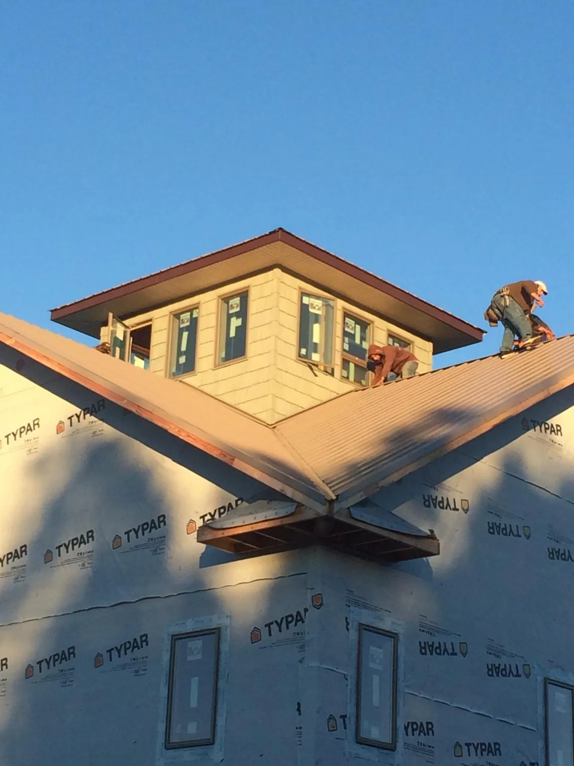 Roofers working around a rooftop cupola on a new metal roof at sunset — Roof Waterproofing in Ukiah by Roofing Brothers